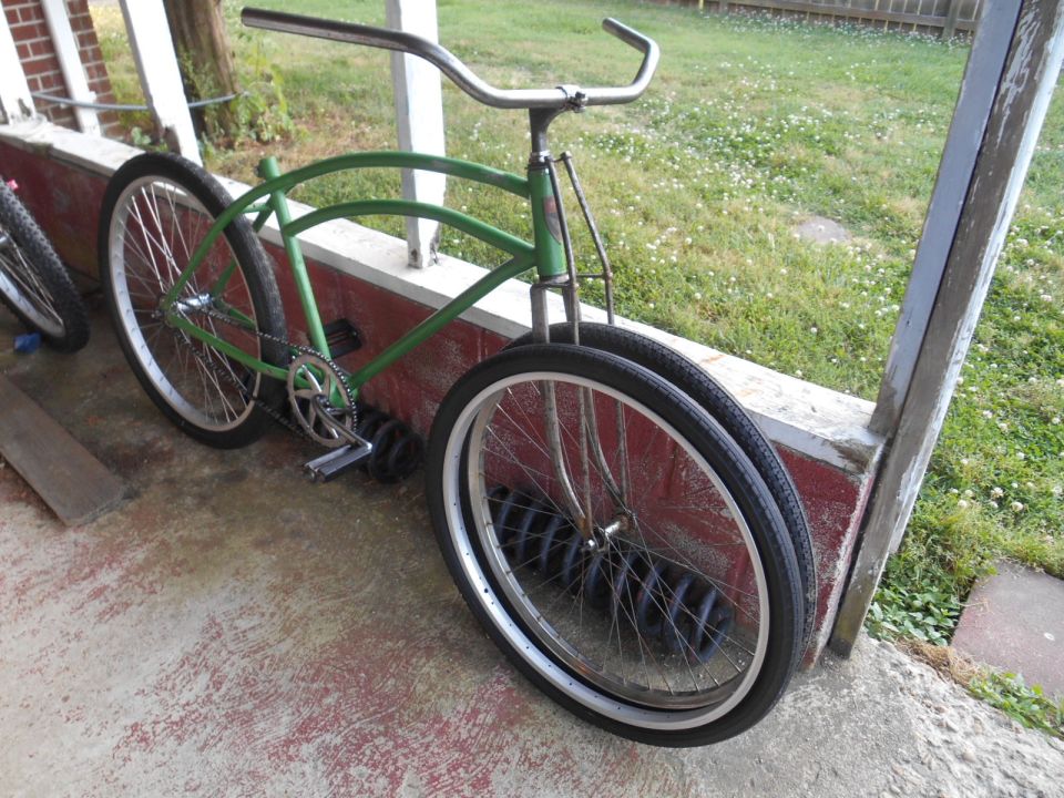 Green cruiser bicycle with chrome handlebars, parked on a porch