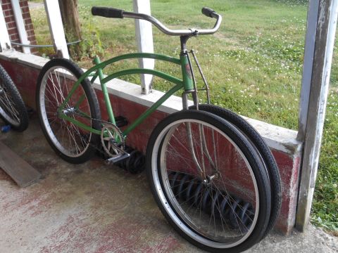 Green bicycle with chrome handlebars and whitewall tires