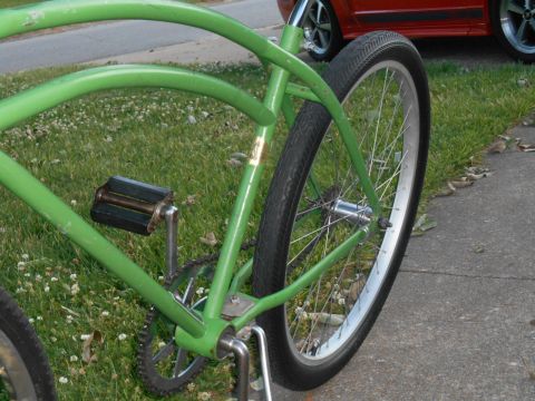 Green vintage bicycle rear wheel, chain, and pedals