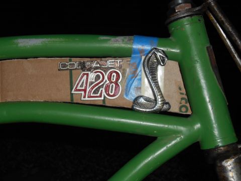 Green bicycle frame with Cobra Jet 428 emblem and chrome cobra figurine.