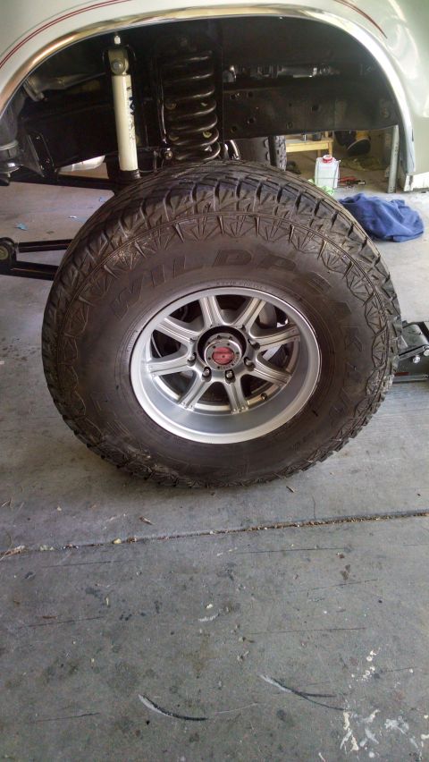 1979 Ford Bronco - A close-up, low-angle view of the front passenger-side tire and suspension of a lifted vehicle, possibly a Ford Bronco, with a silver multi…