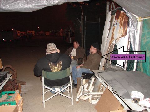 1973 Ford Ranchero - Three men are sitting under a tarp structure at night. One man in the foreground is wearing a black hoodie with an eagle graphic on the bac…