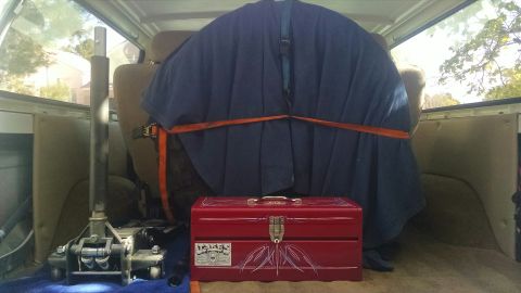 1979 Ford Bronco - The interior of a vehicle, likely a Ford Bronco, is shown with a large, blue tarped object secured with orange straps in the back. A red to…