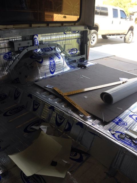 1978 Ford Bronco - The interior of a vehicle is being soundproofed with silver and blue insulation. A ruler and a roll of material are laid out on the floor.