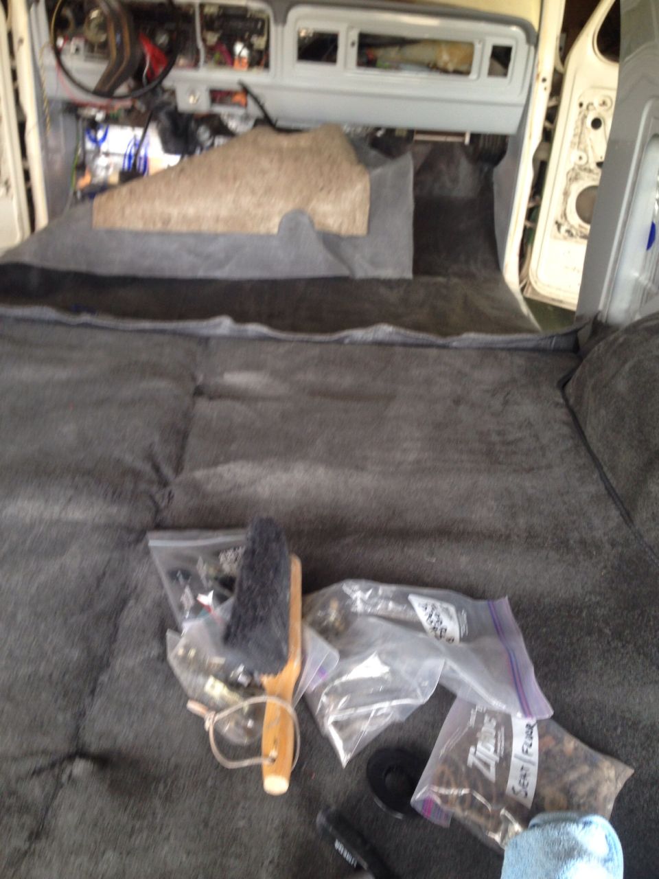 Interior of a classic Ford Bronco with new carpet and parts laid out on the floor.