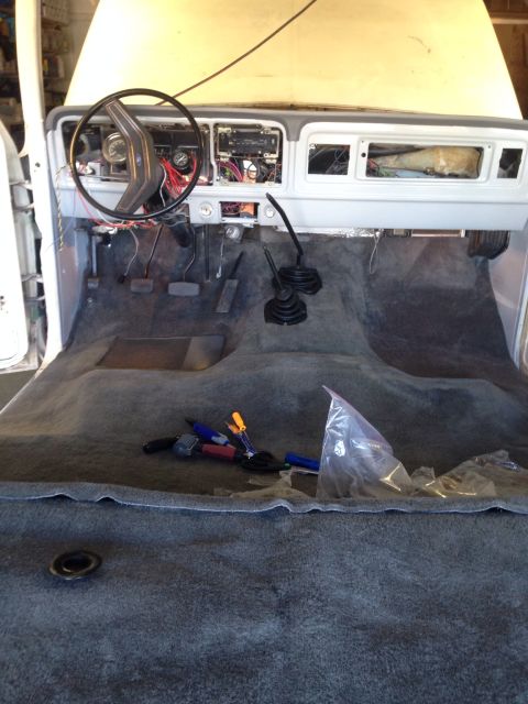 1978 Ford Bronco - The interior of a classic Ford truck or SUV is shown with the dashboard and carpet removed, revealing the wiring and floor. Tools and a pla…
