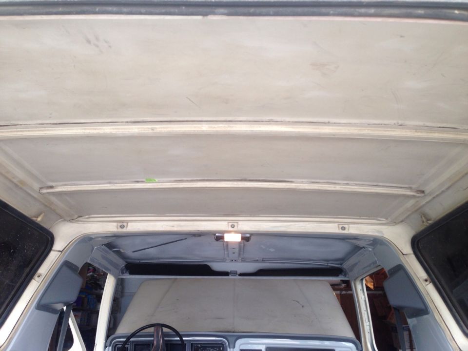 Interior view of a classic vehicle's headliner and upper door frames.