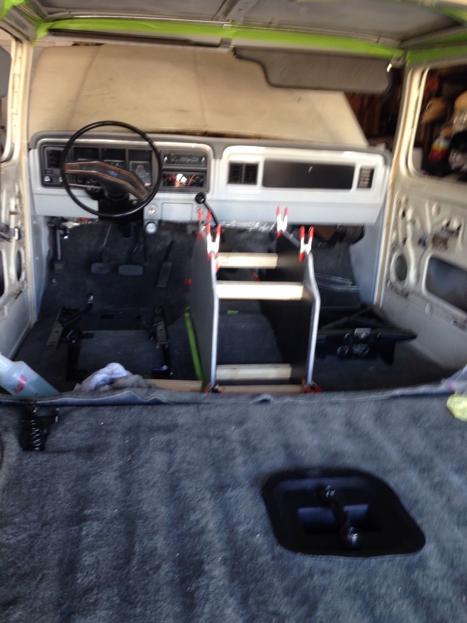 Interior of a classic Ford truck or SUV during restoration, showing dashboard, steering wheel, and floor.