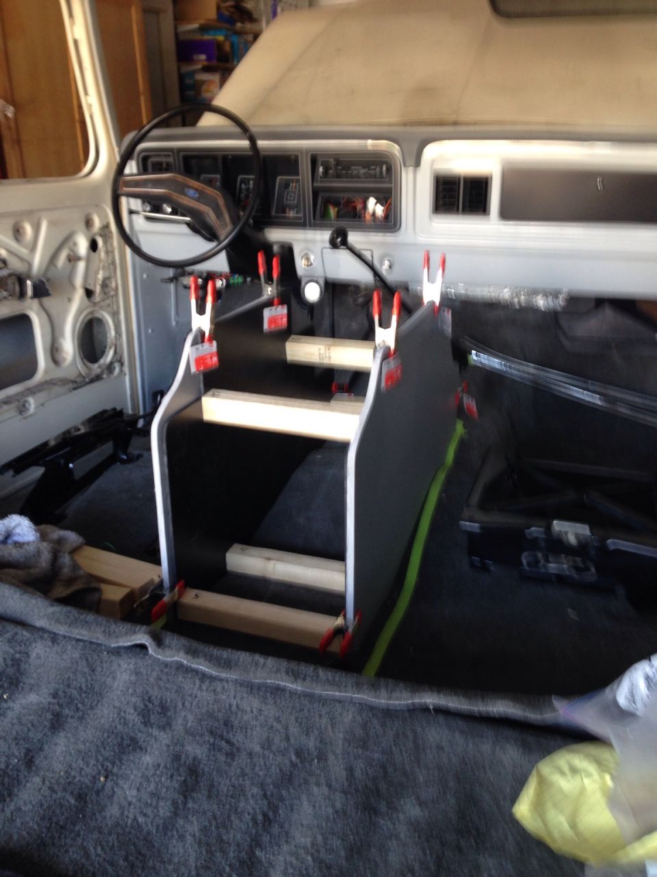 Interior of a classic Ford Bronco with a custom console being assembled.