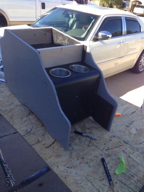1978 Ford Bronco - A custom-built center console with two cup holders is shown in the foreground, positioned in front of a cream-colored sedan. The console ap…