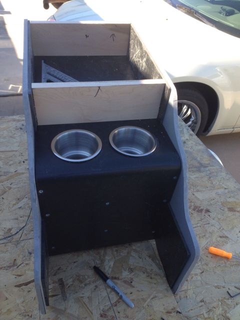 1978 Ford Bronco - A custom-built center console with two stainless steel cup holders is shown in progress, resting on a plywood surface. The console appears…