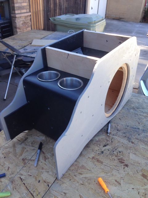 1978 Ford Bronco - A custom-built center console with two cup holders and a large circular cutout for a speaker is shown on a wooden surface. The console appe…