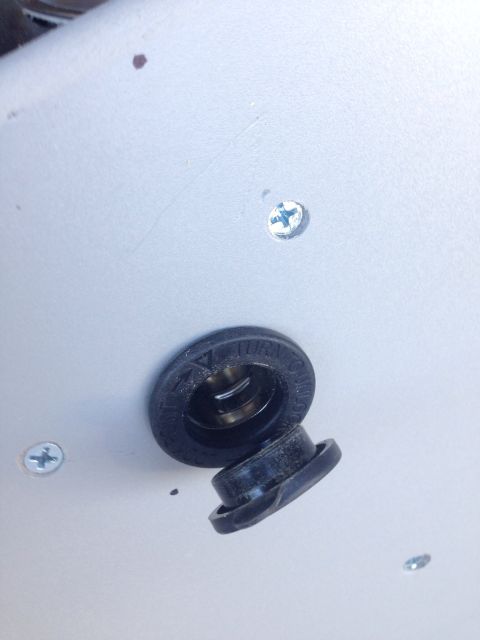 1978 Ford Bronco - A close-up view of a black rubber plug, partially detached from its housing, revealing a metallic interior. The housing has embossed text t…
