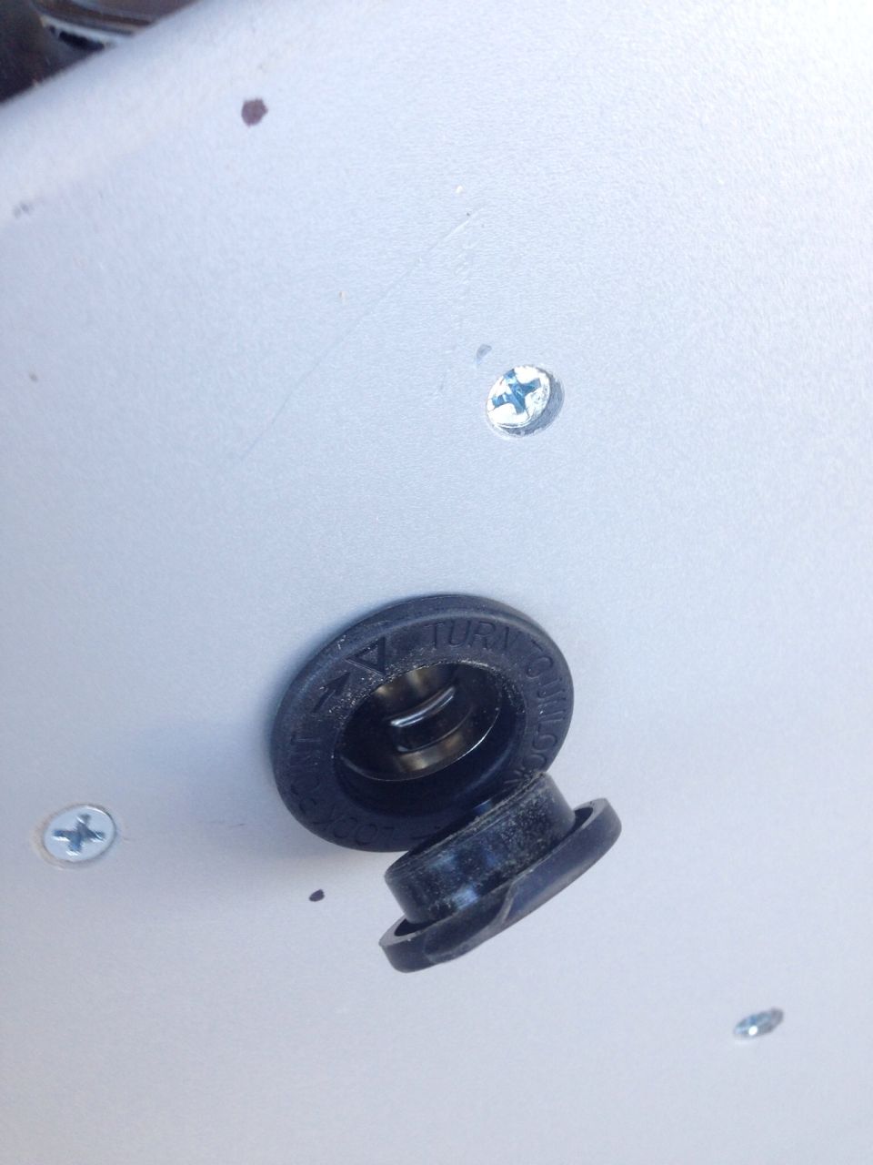 Close-up of a detached black rubber plug with text "TURN TO UNLOCK" and "TURN TO LOCK".