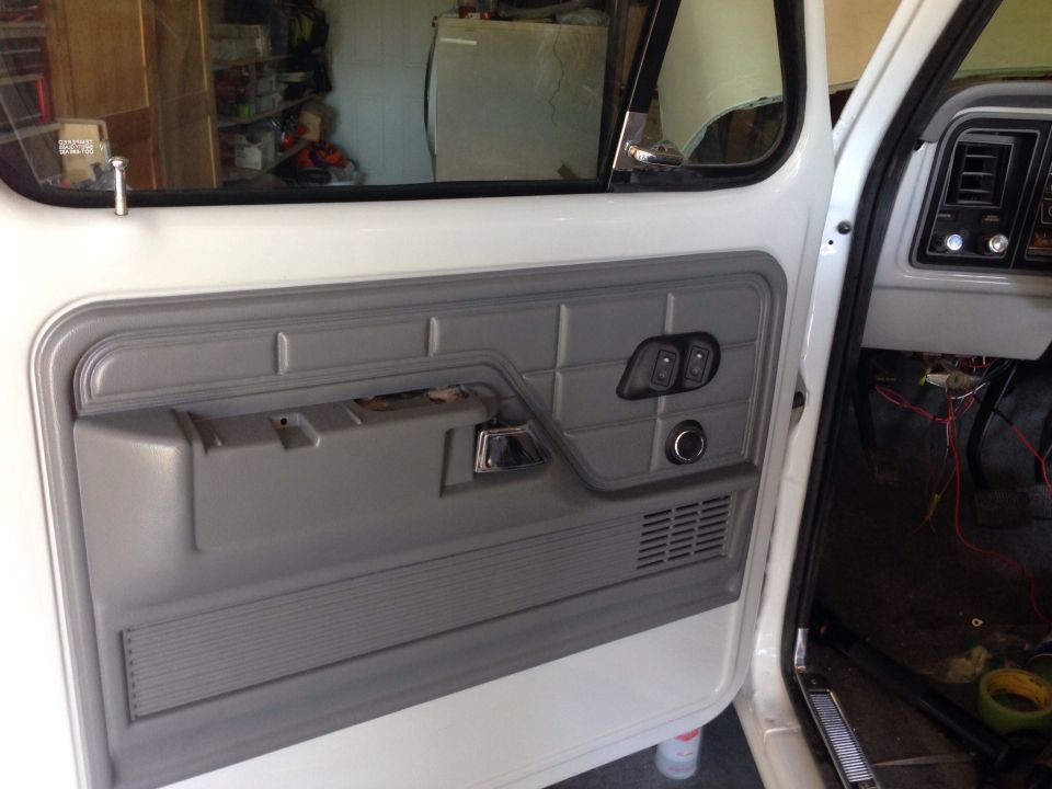 Interior of a white Ford truck door with gray panel, chrome handle, and window controls.