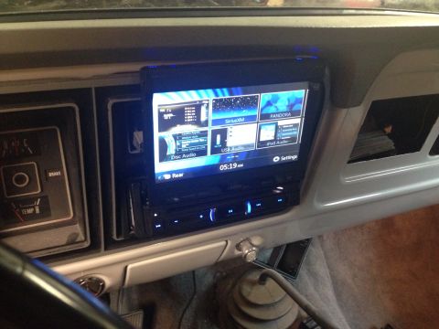 1978 Ford Bronco - The interior of a vehicle shows a modern touchscreen car stereo installed in the dashboard. The stereo displays various audio source option…
