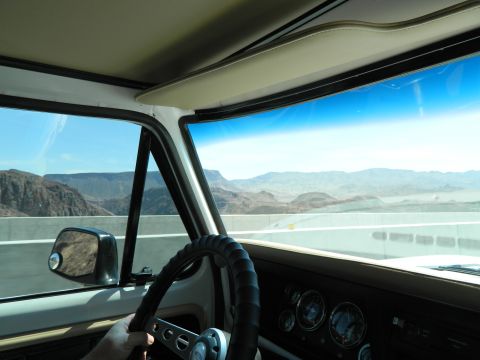 1979 Ford Bronco - Interior view from the driver's seat of a classic vehicle, looking out at a desert landscape. The dashboard features multiple gauges and a…
