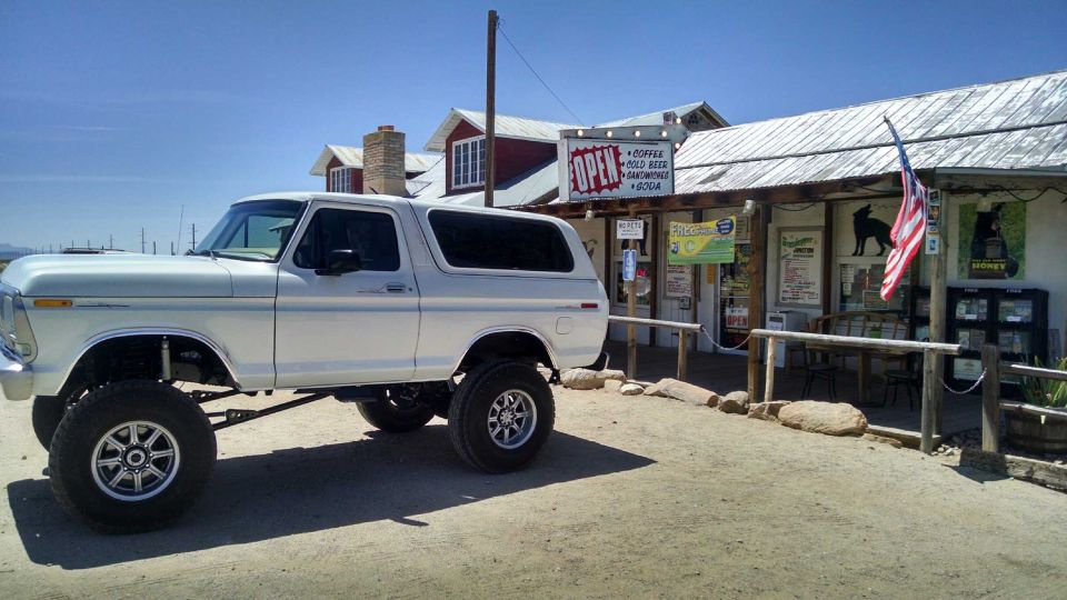 Lifted white 1979 Ford Bronco parked in front of a general store.