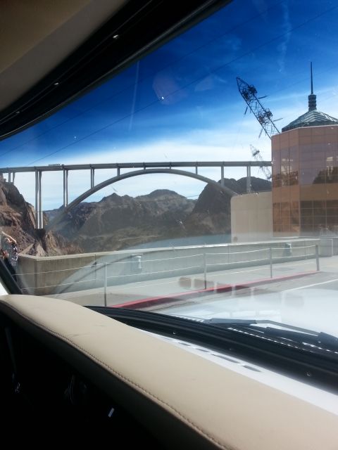 1979 Ford Bronco - A view through a windshield of a bridge spanning a canyon, with a building and construction crane visible in the distance.