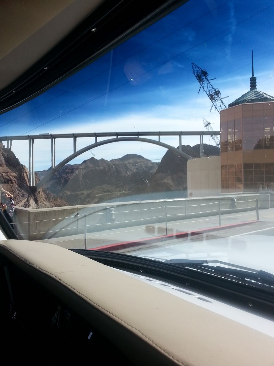 View through windshield of bridge, canyon, building, and crane.