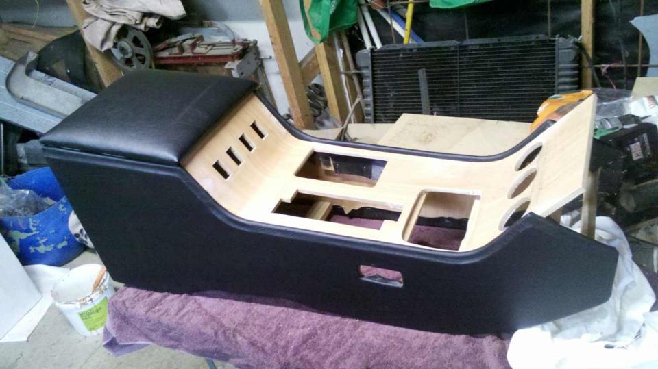 Custom center console with black top and wood interior, featuring cutouts and vents.