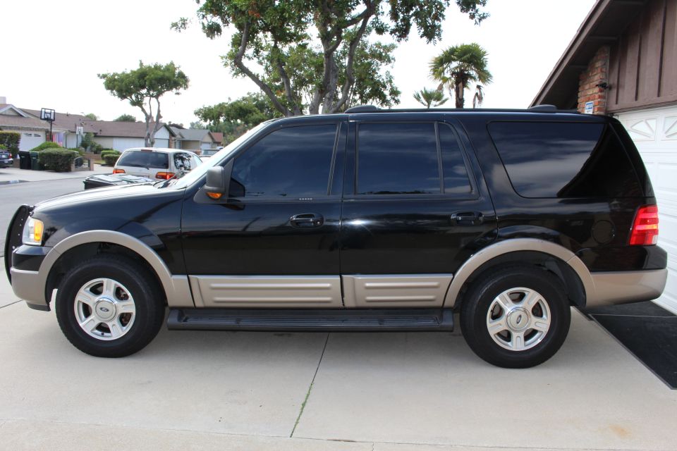 Black Ford Expedition SUV parked on a concrete driveway.