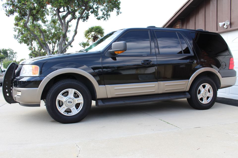 Black Ford Expedition SUV parked on a concrete driveway.
