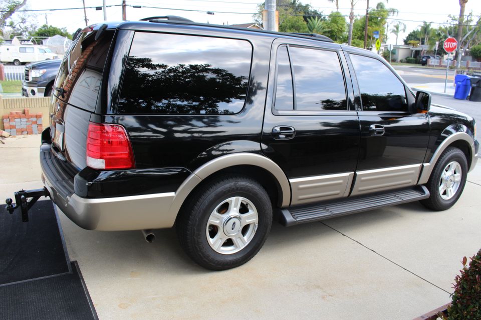 Black Ford Expedition SUV, rear passenger side view, with trailer hitch.