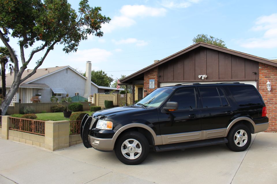 Black Ford Expedition SUV with tan trim and bull bar parked in a driveway.