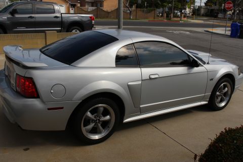 2002 Ford Mustang - The rear driver's side quarter panel and side of a silver Ford Mustang convertible is shown from a low angle. The car has tinted windows an…