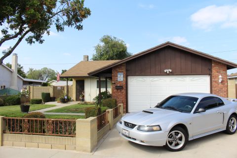 2002 Ford Mustang - A silver 2002 Ford Mustang GT coupe is parked in the driveway of a single-family home. The car is positioned at a three-quarter front angle…