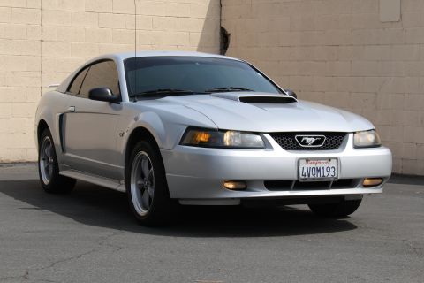 2002 Ford Mustang - A silver 2002 Ford Mustang GT is captured from a three-quarter front view, parked outdoors.