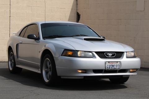 2002 Ford Mustang - This silver 2002 Ford Mustang coupe features a distinctive hood scoop and is captured in a three-quarter front view.