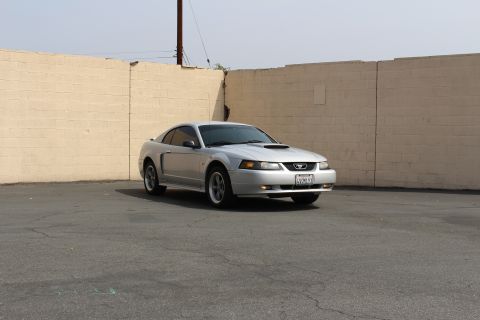 2002 Ford Mustang - A silver 2002 Ford Mustang is captured from a three-quarter front angle in an outdoor lot.