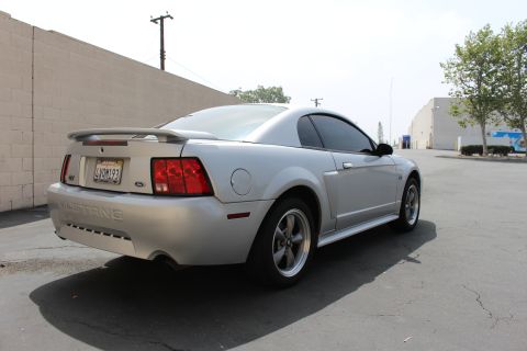 2002 Ford Mustang - Rear 3/4 view of a silver 2002 Ford Mustang coupe with a spoiler and tinted windows.