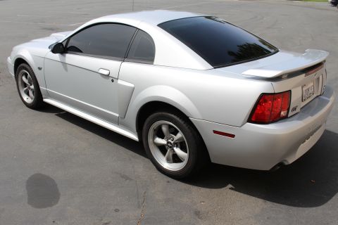 2002 Ford Mustang - A silver 2002 Ford Mustang GT coupe is shown from the rear three-quarter angle on a paved surface.