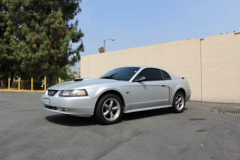2002 Ford Mustang - Silver 2002 Ford Mustang coupe parked outdoors, showing its front and side profile.