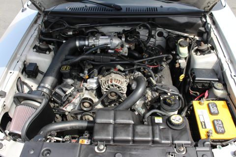 2002 Ford Mustang - Engine bay view of a vehicle, an aftermarket air intake system and a prominent yellow battery.