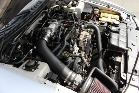 2002 Ford Mustang - The engine bay of a 2002 Ford Mustang is visible, an aftermarket air intake system and other engine components.