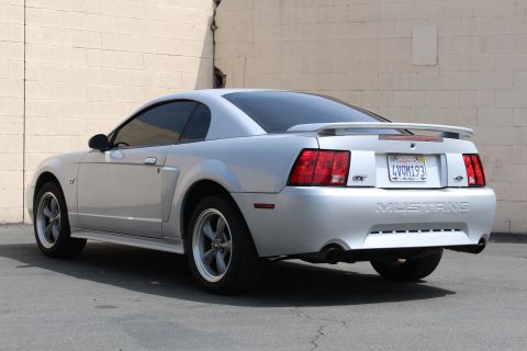 2002 Ford Mustang - Silver 2002 Ford Mustang GT coupe parked outdoors, showing its rear and side profile.