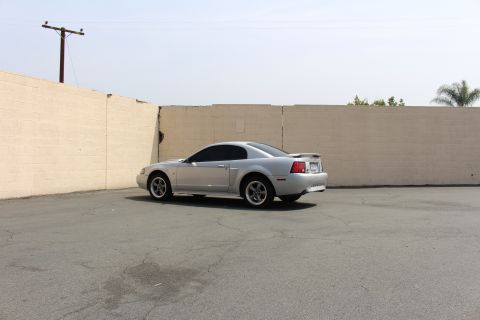 2002 Ford Mustang - A silver 2002 Ford Mustang coupe is parked in an outdoor lot, viewed from the rear three-quarter angle.