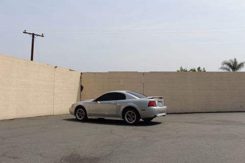 2002 Ford Mustang - Silver 2002 Ford Mustang parked in an outdoor lot with a concrete wall in the background.