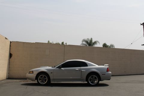 2002 Ford Mustang - Side view of a silver 2002 Ford Mustang coupe parked next to a tan wall.