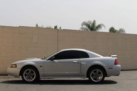 2002 Ford Mustang - Side view of a silver 2002 Ford Mustang coupe with tinted windows and a rear spoiler.