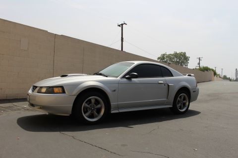 2002 Ford Mustang - This silver 2002 Ford Mustang coupe features a distinctive hood scoop and is captured in a three-quarter front view.