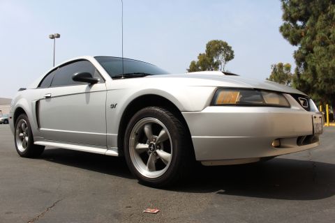 2002 Ford Mustang - A silver 2002 Ford Mustang GT coupe is shown from the front 3/4 angle.