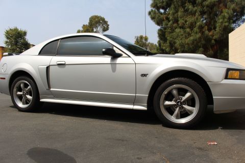 2002 Ford Mustang - Side profile of a silver 2002 Ford Mustang GT coupe parked outdoors.