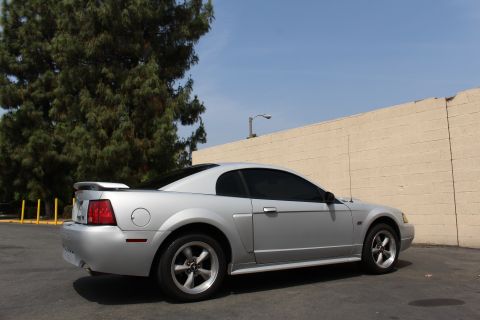2002 Ford Mustang - A silver 2002 Ford Mustang is shown from a three-quarter front view, parked next to a beige wall.