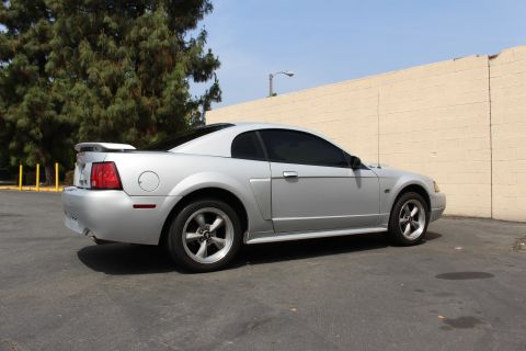 2002 Ford Mustang - A silver 2002 Ford Mustang coupe is seen from its rear-left quarter in an outdoor parking lot.