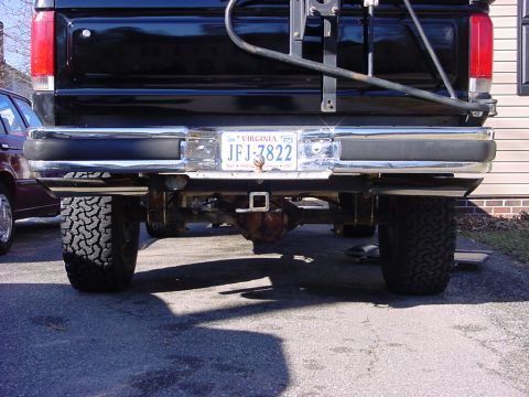 1989 Ford Bronco - The rear of a black pickup truck is shown, a chrome bumper and off-road tires.